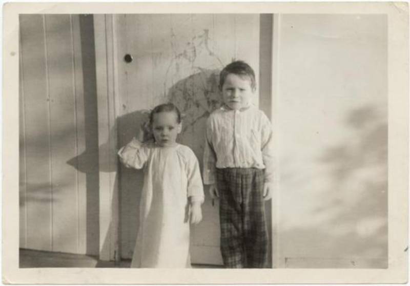 Donna with older brother in front of door